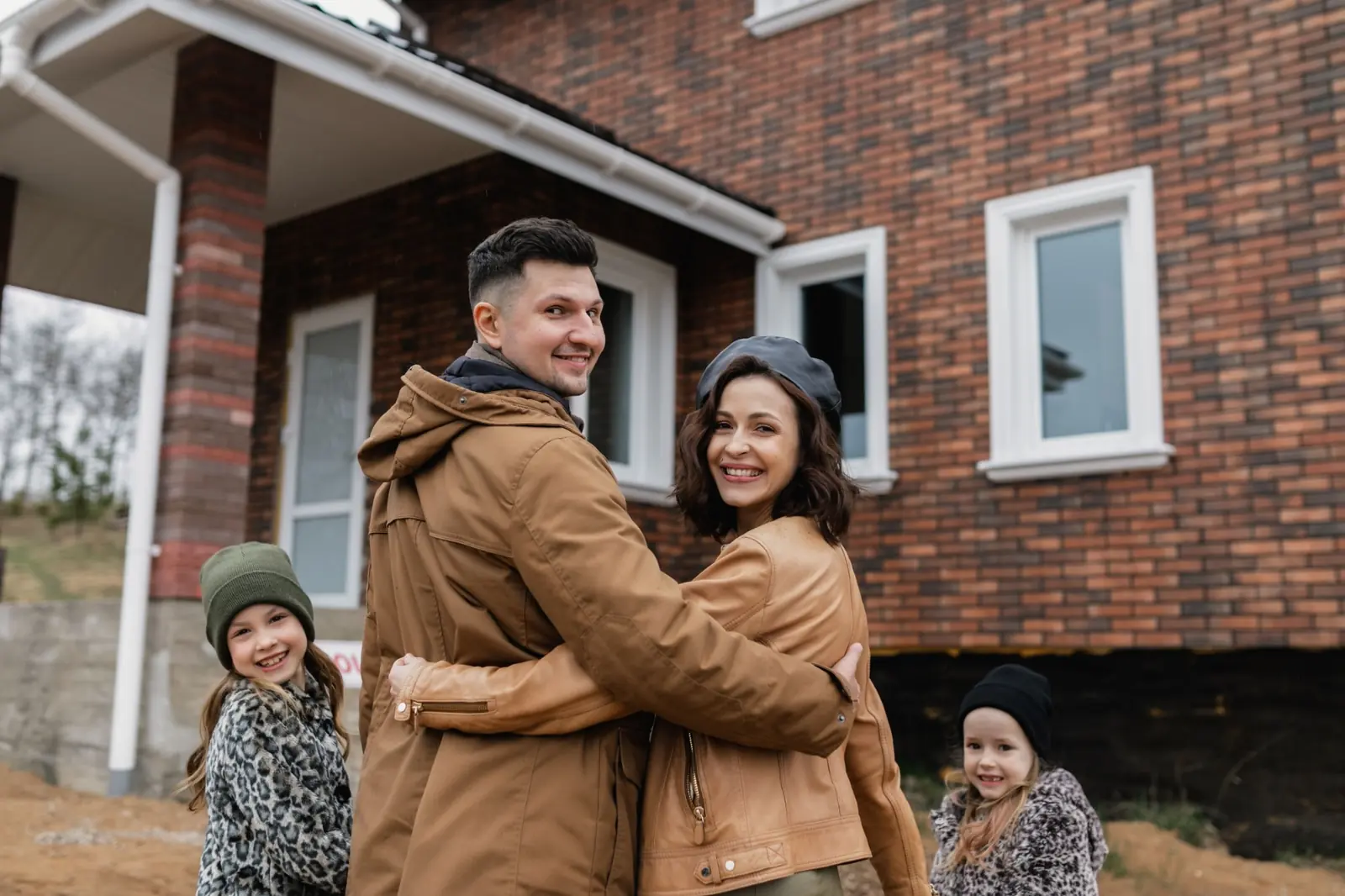 Familie steht lächelnd vor ihrem Haus